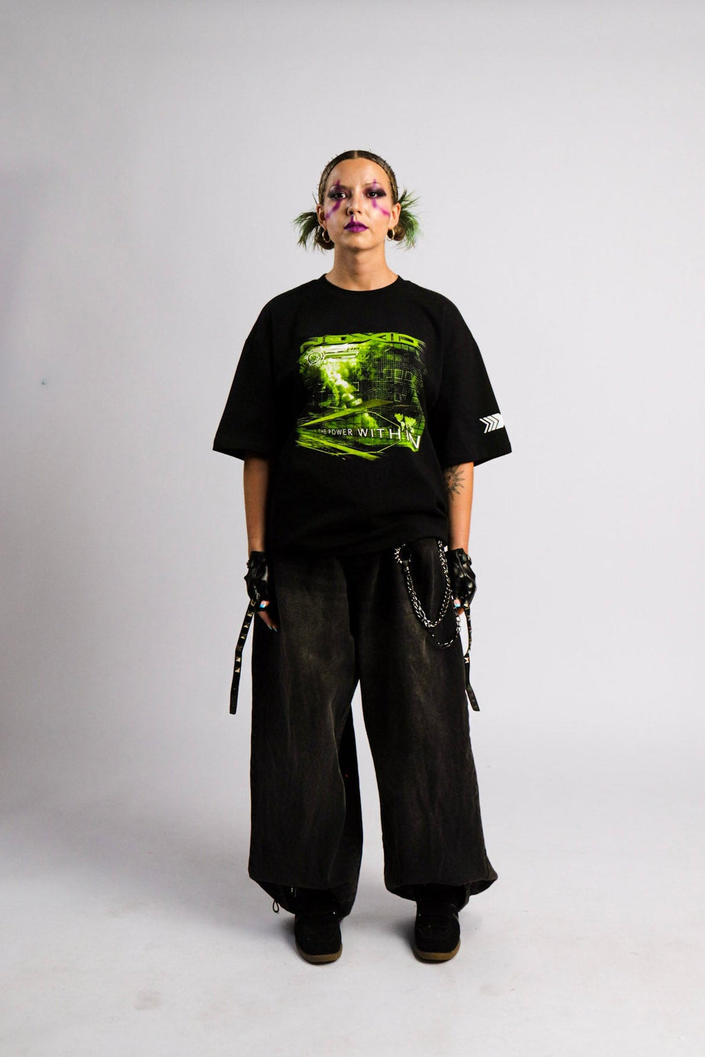 Person wearing a black t-shirt with a graphic design and dark pants on a white background